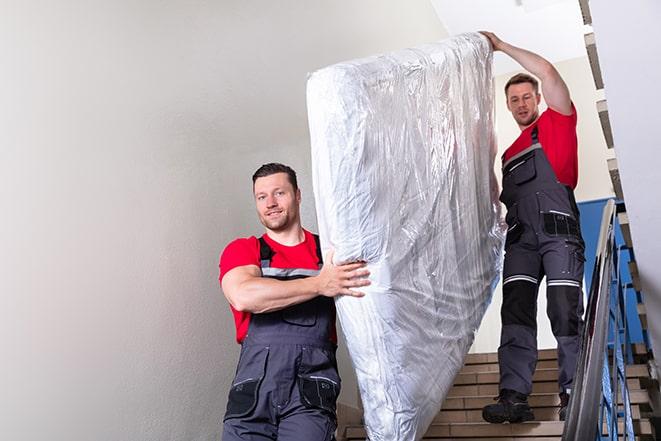 two workers lifting a box spring out of a bedroom in Beach Park, IL